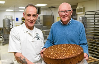 Baker Colin Smith (left) holds the "biggest Dundee Cake ever made" with bakery owner Alan Clark. At 18 inches round and 26lb — or 11.7kg — the World's Largest Dundee Cake is nearly four times as heavy as the weight of an average baby at birth.