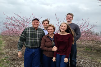  Meet the Angermayer family. "We took this picture on a very chilly and windy spring day when the orchard was in bloom. A peach orchard in bloom smells very nice. Left to right - Mark, son Gabe, Helen, daughter Megan, son-in-law Ian."