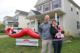 Matthew, Krista and 7-week-old Brooklyn Udermann play host to the World's Largest Mustache at their Chaska home in Clover Ridge.