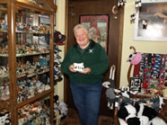 : Ruth Kossner has 7,516 bovine items in her herd, including cookie jars, figurines, wood carvings, wall hangings, toys, games, clothes, books, candles, coffee mugs, pencils, ornaments, floor mats, salt and pepper shakers, and much, much more. In this picture, Ruth is holding a white plaster-type figure of a cow and her calf. She bought it simply because she liked it. 