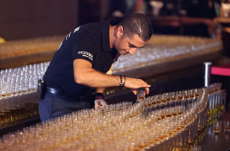  Ahmad Taher, food and beverage manager for Citymax Hotels in Dubai, United Arab Emirates, fixes a shot glass before attempting the world's longest domino drop shot. The Huddle Sports Bar & Grill successfully 'dropped' 4,578 glasses of Camros whiskey into Bazooka energy drink.
