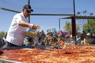  Robert V. Estrada sprinkles cheese over the world s largest flat enchilada Sunday during the 33rd The Whole Enchilada Fiesta in Las Cruces. The making of the giant enchilada returned to the fiesta this year. Last year, the equipment used to make it wasn t ready in time for the state gas commission inspection.