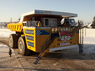 The truck BelAZ-75710 is over 20 meters long, almost ten meters wide, and around eight meters tall. It has a turning radius of approximately 20 meters and a top speed of 64 km/h. Its all-wheel drive and four-wheel hydraulic steering ensure that the tires, which are around four meters tall, don't get stuck in rough terrain. 